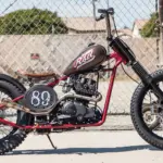 Seitenansicht einer modifizierten Cleveland CycleWerks Heist mit Starrrahmen und markanten Chopper-Elementen vor Maschendrahtzaun