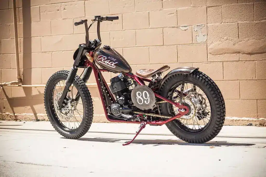Individuell umgebaute Cleveland CycleWerks Heist mit Starrrahmen, Wassell-Tank und Nummernschild 89 vor einer Backsteinmauer