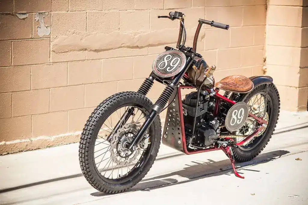Cleveland Heist Chopper-Umbau mit Starrrahmen, individueller Ledersitzbank und Startnummer 89 vor einer Backsteinwand
