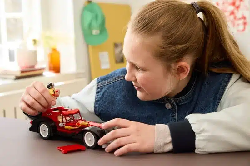 Kind spielt mit dem LEGO Disney Set 43277: Cruella de Vil Auto samt Minifiguren.