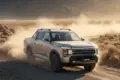 DONGFENG Rich 9 Pick Up beim Fahren auf einer staubigen Piste im Gelände, umgeben von Felsen und Bergen.