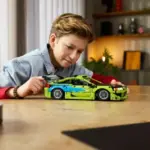 Ein Junge steuert das aufgebaute LEGO Technic Modell des Mitsubishi Eclipse aus Fast & Furious auf einem Tisch.