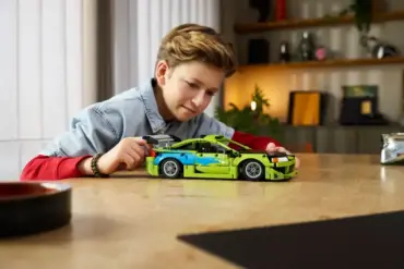 Ein Junge steuert das aufgebaute LEGO Technic Modell des Mitsubishi Eclipse aus Fast & Furious auf einem Tisch.