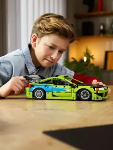 Ein Junge steuert das aufgebaute LEGO Technic Modell des Mitsubishi Eclipse aus Fast & Furious auf einem Tisch.