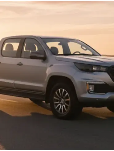 Foton 3 Pick-up in Silber fährt bei Sonnenuntergang auf einer Landstraße in ländlicher Umgebung.