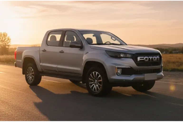 Foton 3 Pick-up in Silber fährt bei Sonnenuntergang auf einer Landstraße in ländlicher Umgebung.
