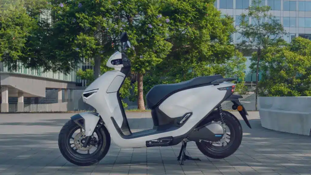 Seitenansicht des weißen Honda CUV e: Elektrorollers im modernen Stadtambiente.