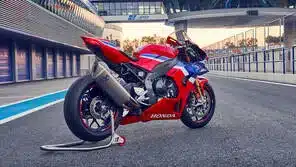 Honda CBR1000RR-R Fireblade Motorrad in rot-blau auf einer Rennstrecke, seitliche Heckansicht.