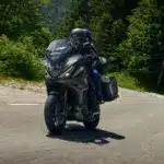Honda NT1100 2026 mit zwei Fahrern auf Landstraße, Seitenkoffer und Windschutz gut sichtbar.