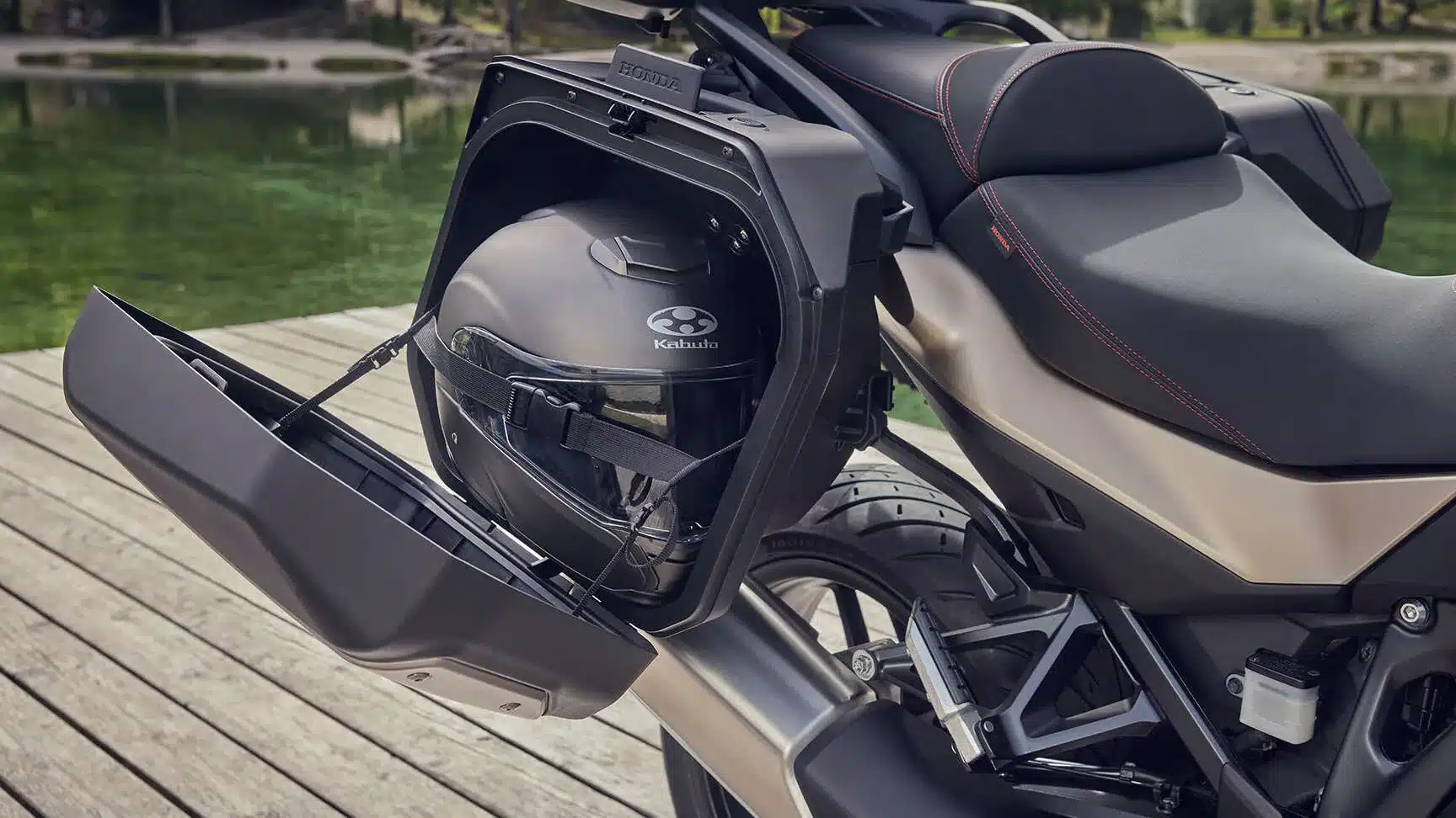 Detailaufnahme eines geöffneten Seitenkoffers an einer Honda NT1100 2026, mit einem verstauten Integralhelm.