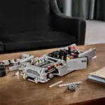 Halb aufgebautes LEGO Modell des James Bond Aston Martin DB5 auf einem Holztisch, umgeben von Einzelteilen.
