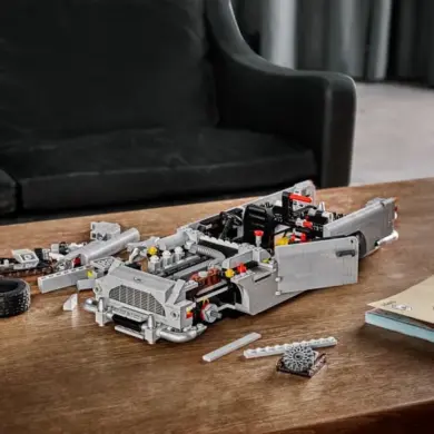 Halb aufgebautes LEGO Modell des James Bond Aston Martin DB5 auf einem Holztisch, umgeben von Einzelteilen.