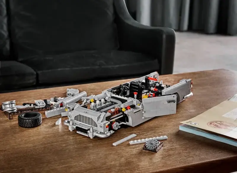 Halb aufgebautes LEGO Modell des James Bond Aston Martin DB5 auf einem Holztisch, umgeben von Einzelteilen.