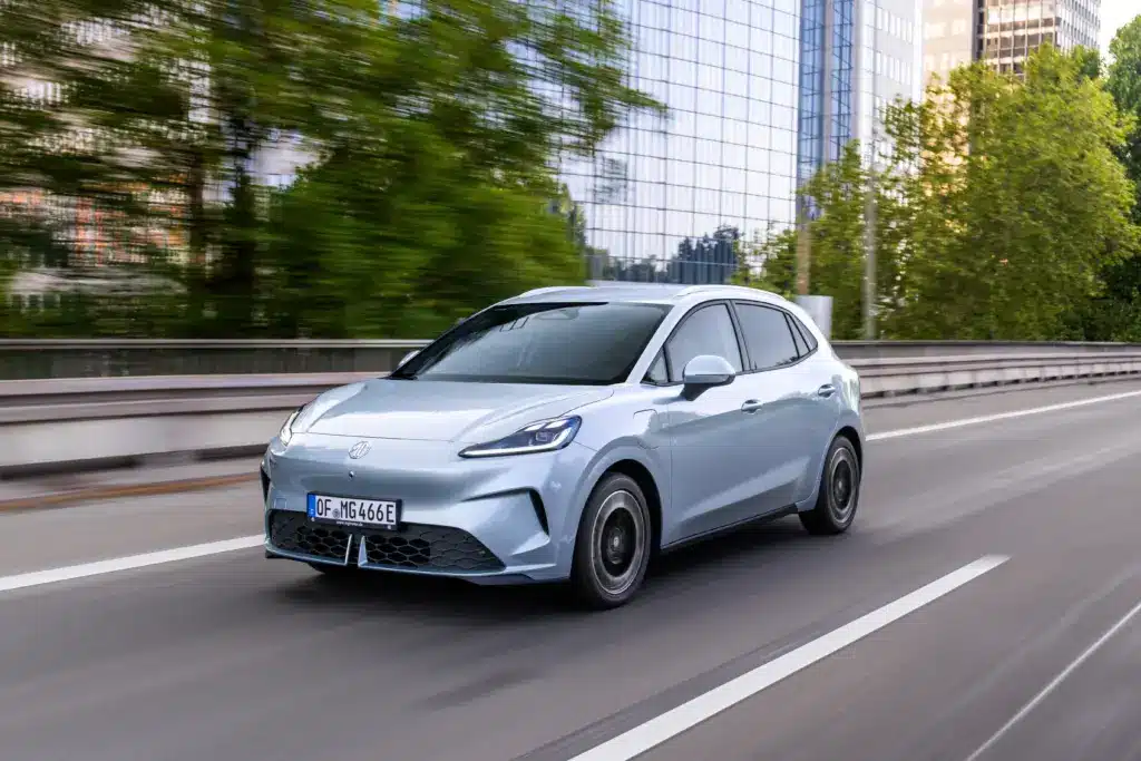 MG4 EV Elektroauto fährt auf einer Straße, aufgenommen in einer modernen Stadtumgebung.