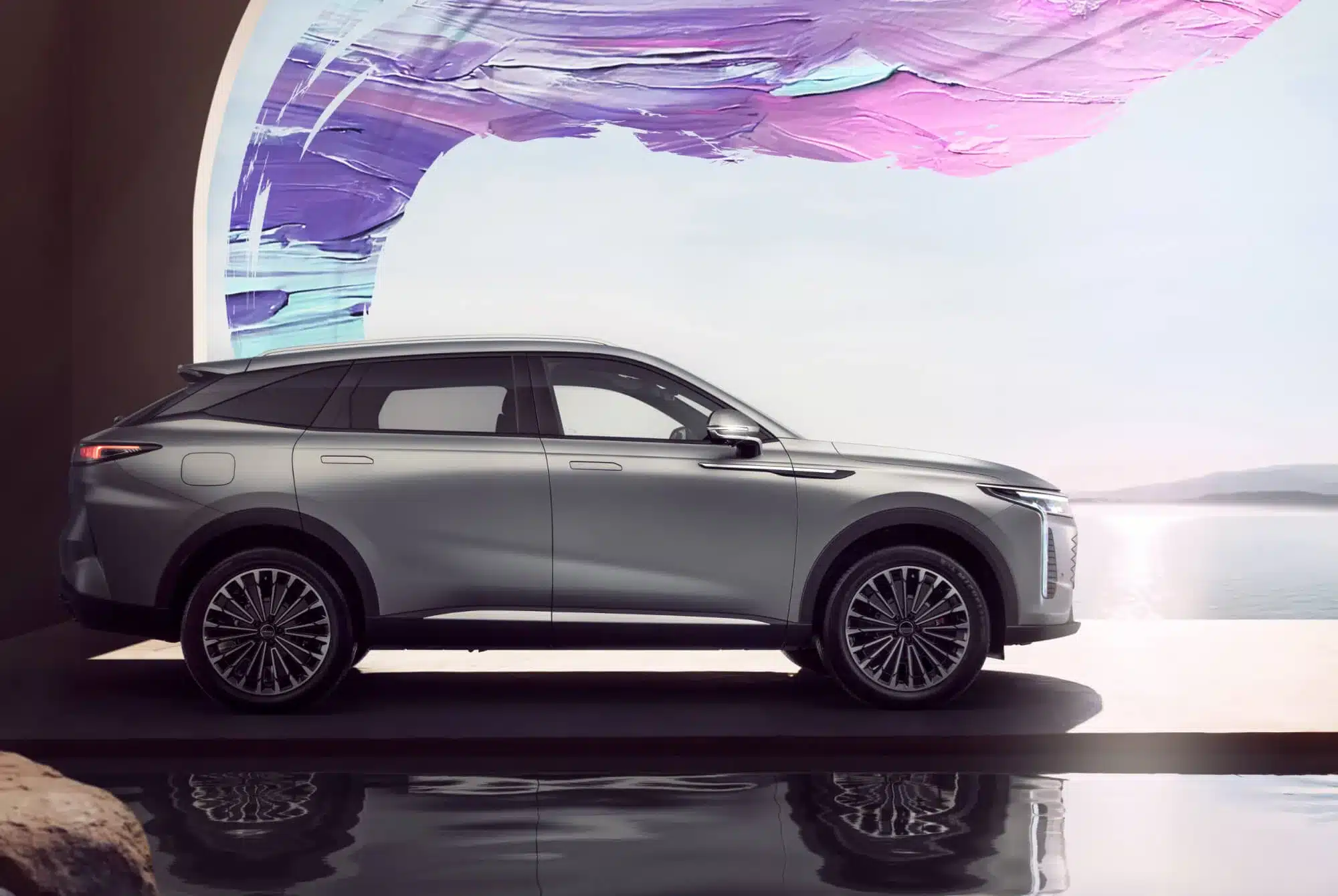 OMODA 9 PHEV SUV in Silber, seitliche Aufnahme am Wasser vor künstlerischem Hintergrund