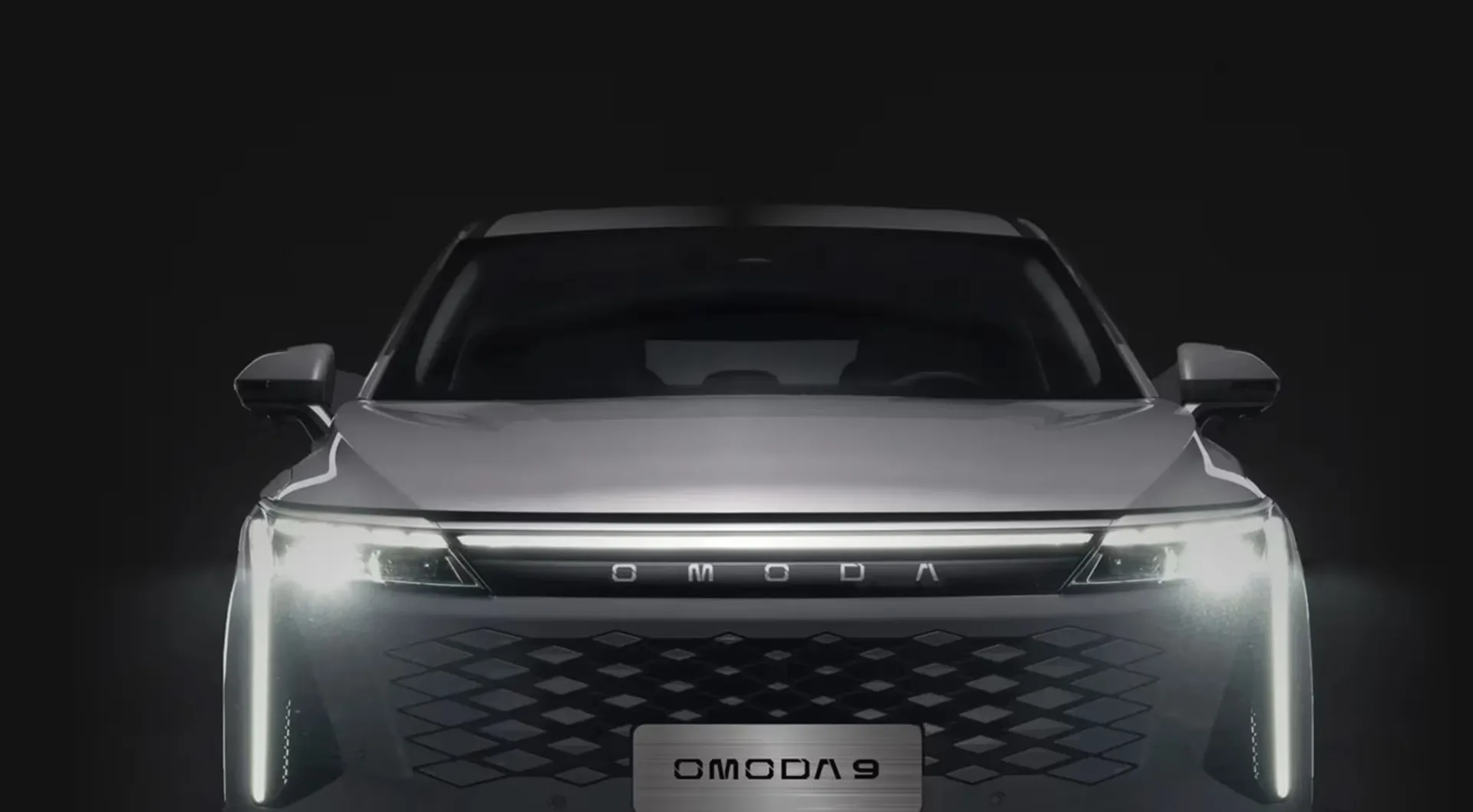 Front des OMODA 9 PHEV mit beleuchtetem Kühlergrill und T-förmigen LED-Scheinwerfern