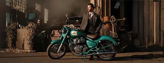 Royal Enfield Classic 650 Motorrad in Bruntingthorpe Blue mit Fahrer im Anzug in urbaner Umgebung