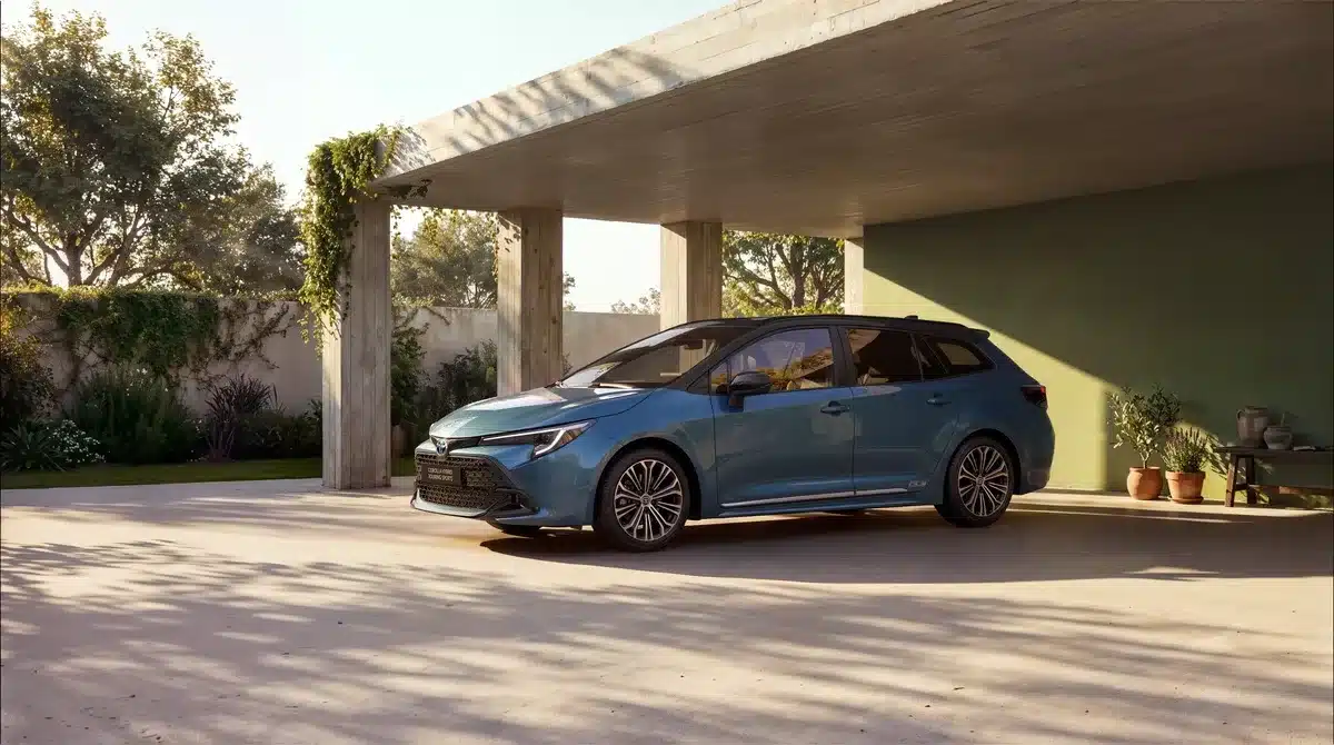 Toyota Corolla Touring Sports 60th Anniversary in New Boreal Blue Metallic mit schwarzem Dach, Seitenansicht, geparkt unter Carport.