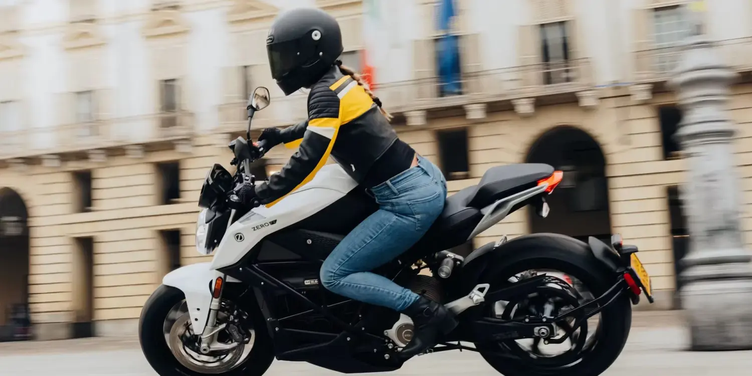 Fahrerin auf einer weißen Zero S Z-Force 15,6+ 11 kW fährt durch die Stadt.